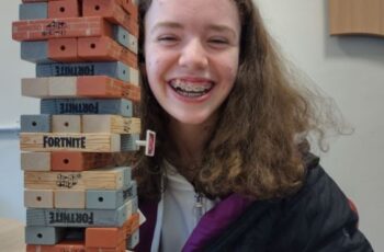 Young person E smiling behind table with Fortnite jenga blocks stacked