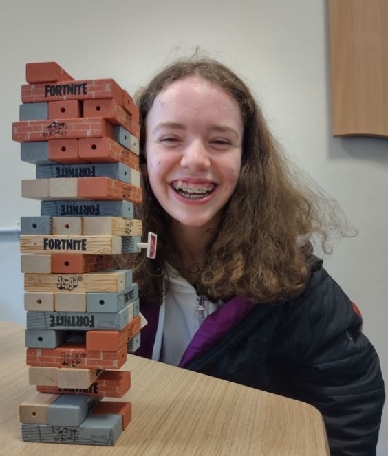 Young person E smiling behind table with Fortnite jenga blocks stacked